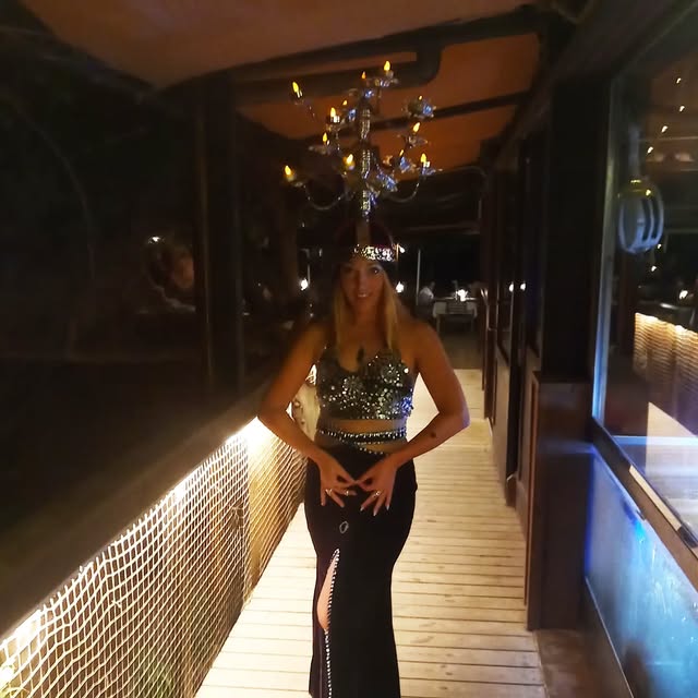 Bailarina con un traje negro adornado con pedrería, manteniendo un candelabro encendido en equilibrio.
